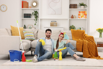 Spring cleaning. Couple with detergents and mop in living room - obrazy, fototapety, plakaty