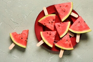 Plate with sweet watermelon sticks on grey background