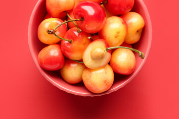 Naklejka na ściany i meble Bowl with sweet yellow cherries on red background