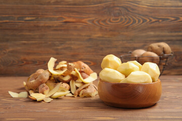 Bowl with peeled potatoes on wooden background