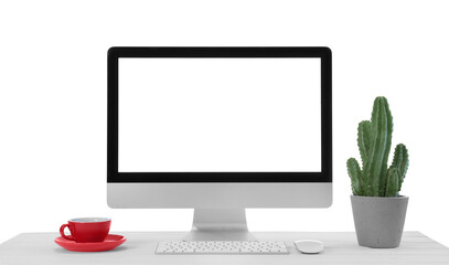 Computer, potted cactus and cup of drink on table against white background. Stylish workplace
