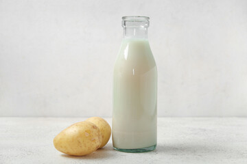 Bottle of tasty potato milk on light background