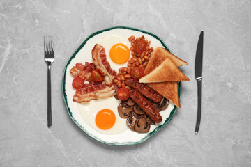 Plate of fried eggs, mushrooms, beans, bacon, sausages and toasts served on grey marble table, flat lay. Traditional English breakfast