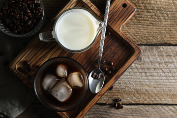 Delicious iced coffee, milk and beans on wooden table, flat lay