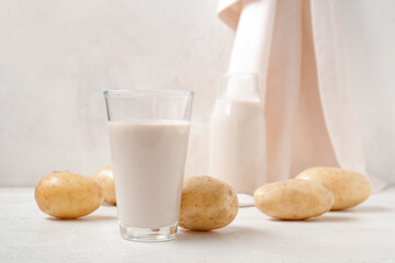 Glass of tasty potato milk on light background
