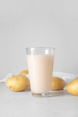 Glass of tasty potato milk on light background