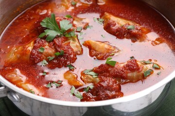 Delicious stuffed cabbage rolls cooked with homemade tomato sauce in pot, closeup