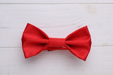 Stylish red bow tie on white wooden table, top view