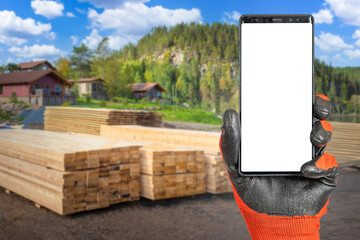 Phone in builder hand. Smartphone mock up. Construction site with logs. Place for building offer....