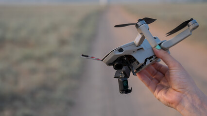 Woman holding crashed drone outdoors. 