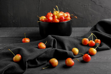 Bowl with sweet yellow cherries on black wooden table