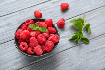 Bowl with fresh raspberry and mint on grey wooden background, closeup