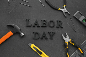 Different tools and text LABOR DAY on black grunge background