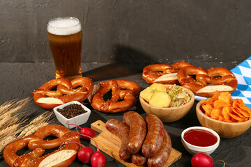 Glass of cold beer and different snacks on black background. Oktoberfest celebration