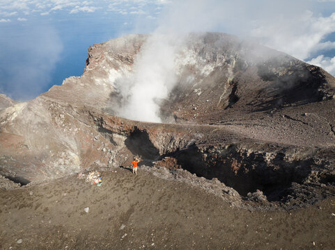 Aerial view of a person standing and looking over ledge of Gamalama volcano in Ternate, Indonesia.