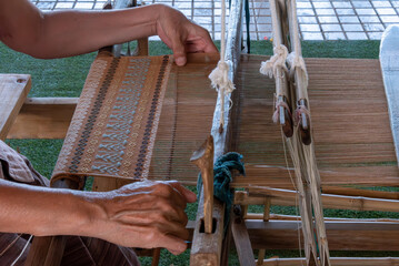 The traditional weaving of handmade cotton on the manual wood loom in Thailand.