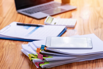 Paper documents are stacked on wooden desks at the workplace.