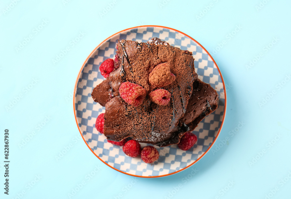 Wall mural Plate with pieces of raspberry chocolate brownie on blue background