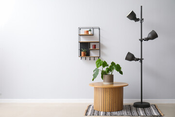 Wooden coffee table with houseplant, standard lamp and shelf near grey wall