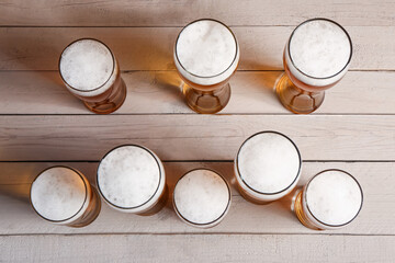 Glasses of cold beer on light wooden background. Oktoberfest celebration