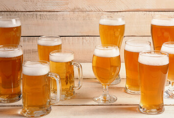 Glasses and mugs of cold beer on light wooden background. Oktoberfest celebration