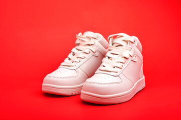 children's high sneakers on red background close-up.