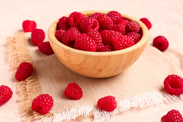 Wooden bowl with fresh raspberries on light background
