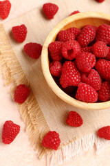 Wooden bowl with fresh raspberries on light background