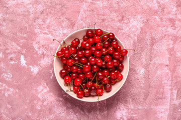 Bowl with red sweet cherries on pink background