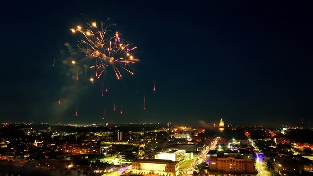 Downtown Des Moines, Iowa buildings at night with fireworks exploding in celebration of Independence Day near Iowa state capitol building with drone video stable.