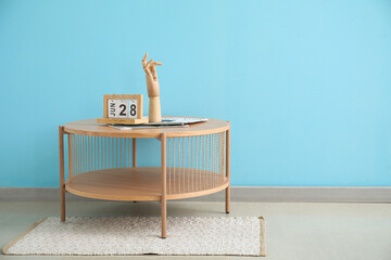 Coffee table with wooden hand and cube calendar near blue wall