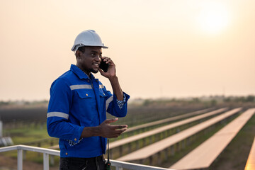Obraz premium African young engineer talking on phone while work at solar cell field. 