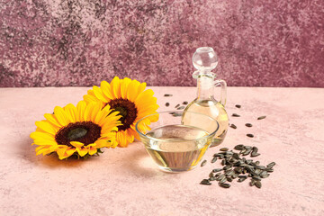 Sunflowers, seeds, bowl and decanter of oil on pink background