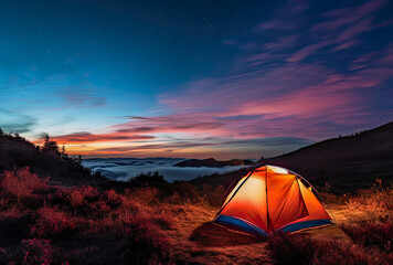 An illuminated tent in the mountains with great views of a lake. Camping is a great way to get closer to nature and enjoy a summer vacation.