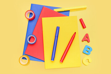 Notebooks with stationery on yellow background