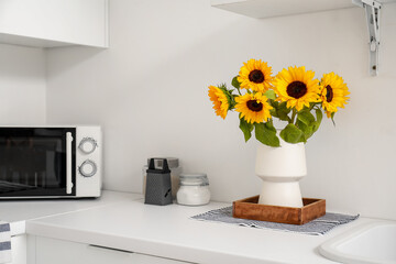 Vase with beautiful sunflowers on white kitchen counter