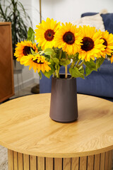 Vase with beautiful sunflowers on wooden coffee table in living room