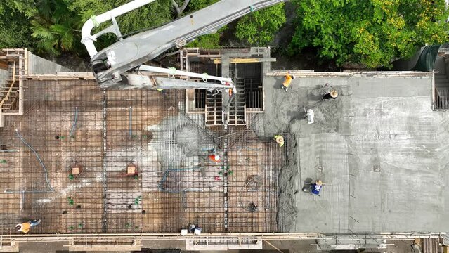 Drone view of construction workers carefully pouring screed over steel reinforcement and leveling surface with special tool. Concept of industry and engineering