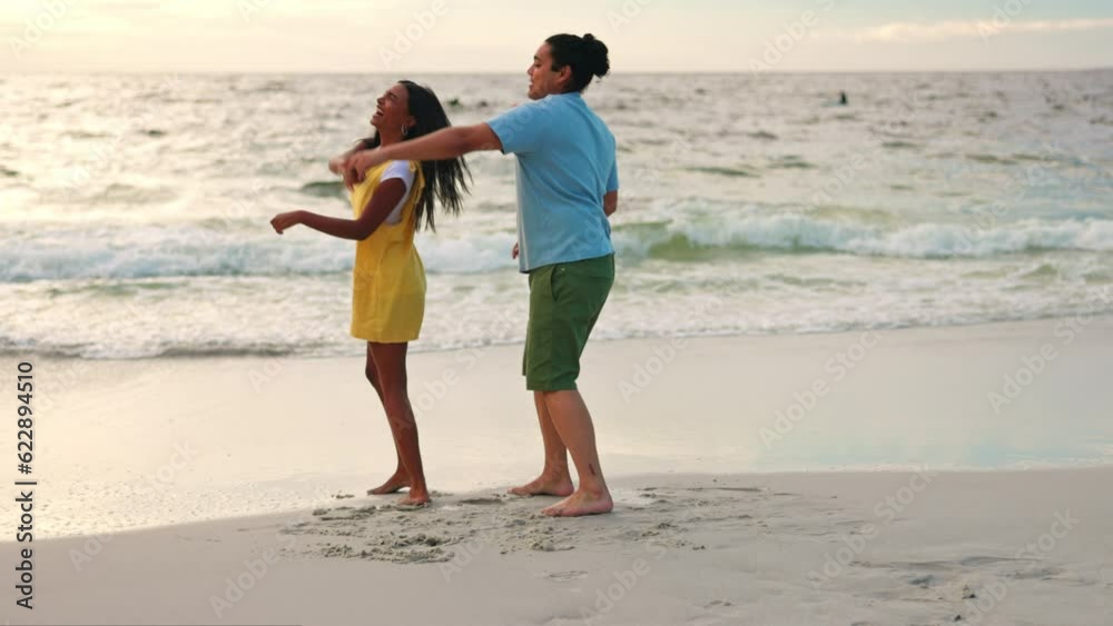 Sticker Happy couple, dance and beach by water for fun holiday, weekend or summer break together in nature. Man and woman holding hands and enjoying bonding in sunset by the waves on the ocean coast outdoors