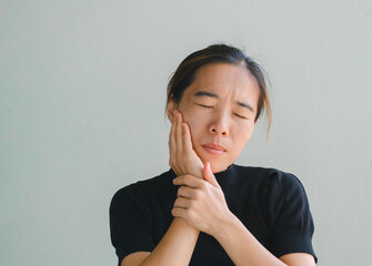 Asian woman puts her hand on her mouth and feels toothache because of tooth decay. Problems with...