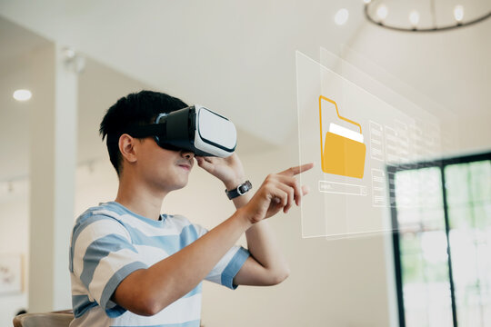 Teenager is opening the files folder from cloud via Virtual reality headset in livingroom, technology and modern lifestyle concept. - Powered by Adobe