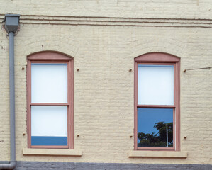 Beige Building with Red arched Windows and a Reflection.