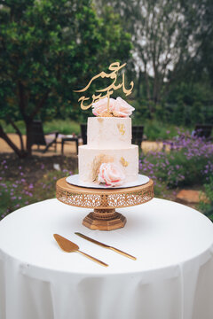 Pink wedding cake with pink roses flowers and gold arabic writing