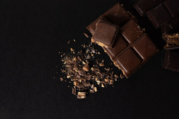 Dark chocolate with peanuts melting towards the center of the image. Visual composition. Black...