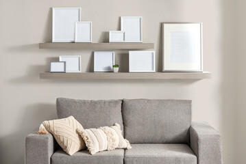 Blank picture frames mockup on shelves inside a modern living room with a couch and an array of decorative pillows