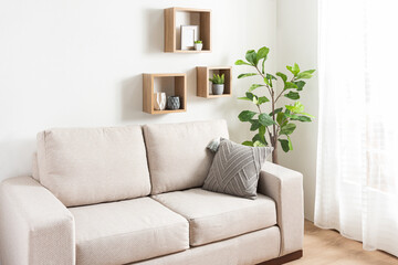 a large cream couch with some cushion on it and shelves of greenery