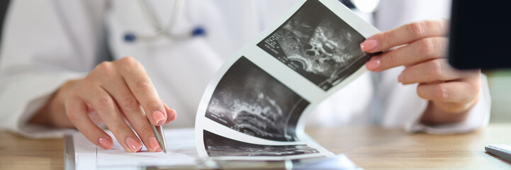 Female doctor with stethoscope doing paperwork, checking medical documents at workplace.