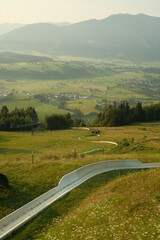 Vertical shot of summer toboggan with the view of green vale. Biberg, Saalfelden, Austria.