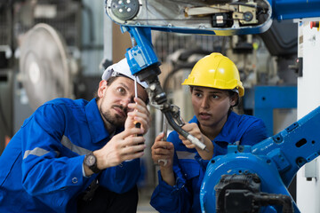 Industrial Manufacturing Robotic Arms Maintaining. Male, female engineer inspecting quality and...