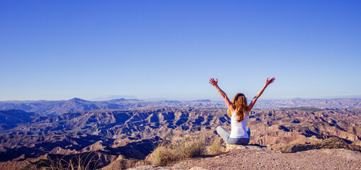 Happy woman sitting with open arms enjoying panoramic view of landscape, desert, canyon- adventure,hiking concept